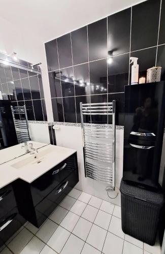 La salle de bains en noir et blanc est pourvue d'un lavabo et d'une douche. dans l'établissement Appartement Hyères, à Hyères
