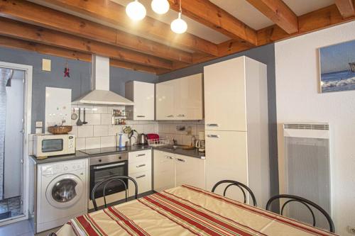 une cuisine avec des armoires blanches et une table et des chaises dans l'établissement Appart 3 pièces, à Capbreton