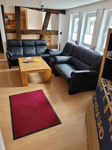 a living room with a black couch and a coffee table at Fereinwohnung mit 5 Schlafzimmern in Schlitz