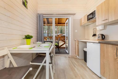 a kitchen with a white table in a tiny house at Domki "Arkadia" in Pobierowo