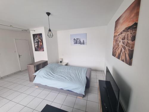une chambre blanche avec un lit et une télévision dans l'établissement Studio Lumineux Bellevue 11, à Saint-Étienne