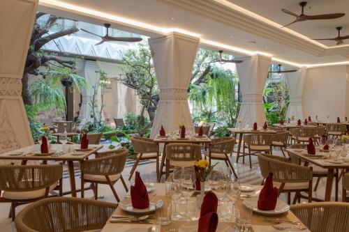 a dining room with tables and chairs and trees at La Plante Siem Reap in Siem Reap