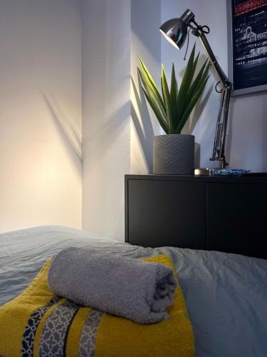 un lit avec une couverture jaune, une lampe et une plante dans l'établissement Le Petit Sphynx - 9m2, à Vichy