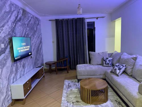 a living room with a couch and a flat screen tv at KOSUHOMEs in Namugongo