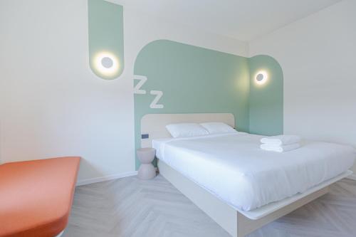 a white bedroom with a bed and a chair at ezzenhotel Phitsanulok in Phitsanulok