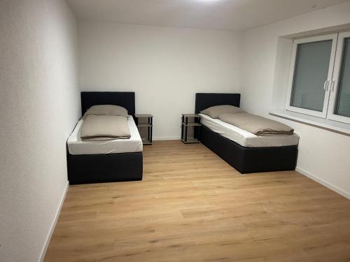 two beds in a room with wooden floors at Sehr schöne und Modernisierte Wohnung mit moderne Wohnraumlüftung in Pfedelbach