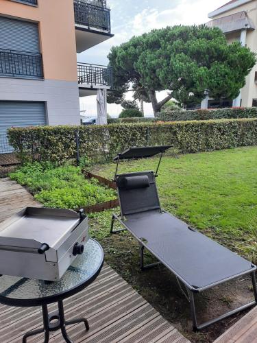 - un barbecue assis sur une table à côté d'une terrasse dans l'établissement Appartement 67 m2 avec 100 m2 jardin privatif RESERVABLE UNIQUEMENT PAR PERIODE DE 7 JOURS MINIMUM DU SAMEDI AU SAMEDI, à Arcachon