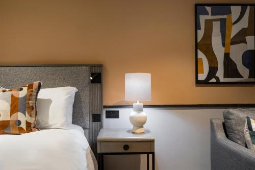 a bedroom with a bed and a table with a lamp at voco Fareham - Solent by IHG in Fareham