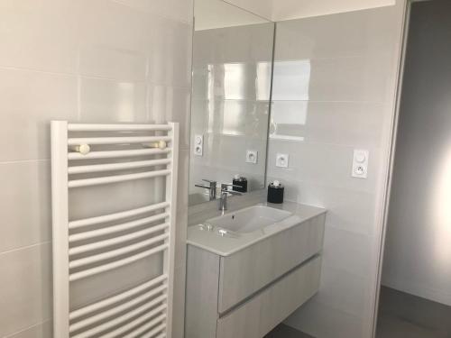 une salle de bain blanche avec un lavabo et un miroir dans l'établissement T3 Tout confort à 5 mn des plages de Pinarello, à Pinarellu