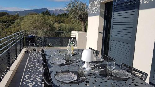 une table avec des assiettes et des verres sur un balcon dans l'établissement T3 Tout confort à 5 mn des plages de Pinarello, à Pinarellu