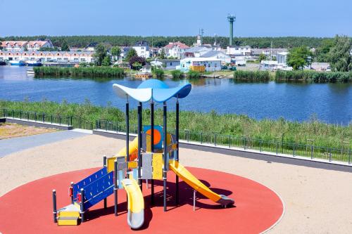 a playground with a slide in front of a river at Apolonia Apartamenty III - SPA in Dziwnów