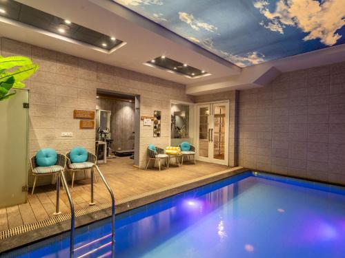 a swimming pool in a hotel room with blue chairs at Moustache Mussoorie in Mussoorie