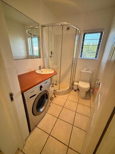 a bathroom with a washing machine and a sink at 120 on Lyme in St Francis Bay