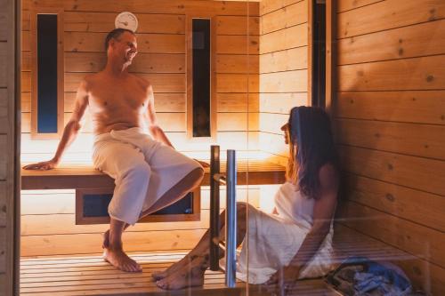 a man and a woman sitting in a sauna at Soul Valley all-in boutique hotel with yoga & wellness in Maracalagonis