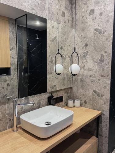 a bathroom with a white sink and two lights at Moho Будинки для відпочинку in Bukovel
