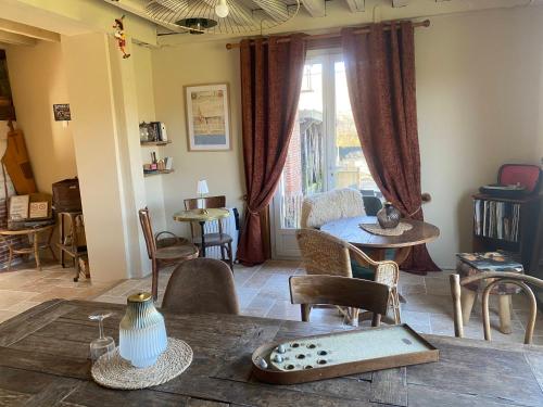 a living room with a table and chairs and a window at Maison La folie douce in Saint-Pierre-de-Manneville