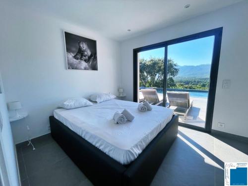 a bedroom with a large bed with a large window at Architect's Villa - 10-12 people - Pool - 4 bedrooms in Zonza