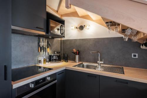 - une cuisine avec des placards noirs et un évier dans l'établissement Apartment Nochebuena, Alpe d'Huez - by EMERALD STAY, à Huez