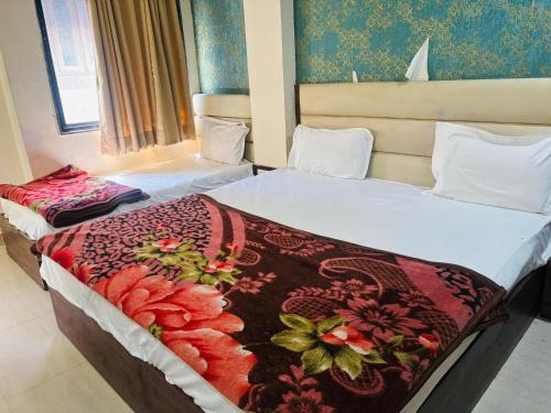a bedroom with two beds with a blanket on them at Hotel Greenwood in Ahmedabad