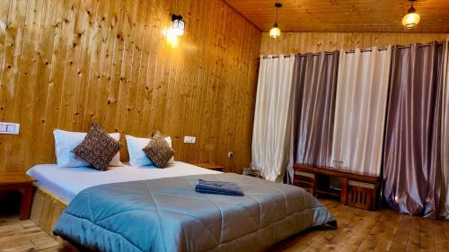 Acoustic heaven Cottage jibhi في Jibhi: غرفة نوم بسرير كبير في غرفة بجدران خشبية