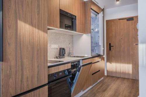 a kitchen with wooden cabinets and a sink at Noli Gdansk Wrzeszcz in Gdańsk