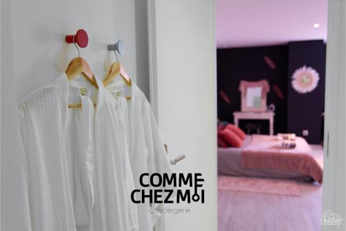 une chambre avec des robes blanches suspendues à une porte dans l'établissement Suite Le Cocon & Spa, à Nancy