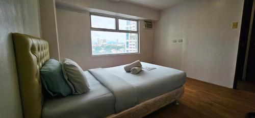 a bed in a room with a window at Gilmore Tower Suites By SMS Hospitality in Quezon City
