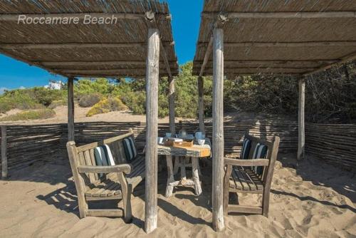 a table and chairs sitting under a roof on the beach at Villa Rocchetta in Casa Mora