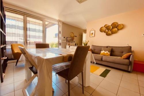 une salle à manger avec une table et un canapé dans l'établissement Quiet house with terrace and south-facing garden, à La Rochelle