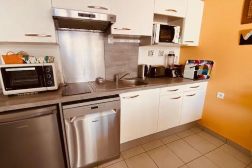 une cuisine avec un évier et un micro-ondes dans l'établissement Quiet house with terrace and south-facing garden, à La Rochelle