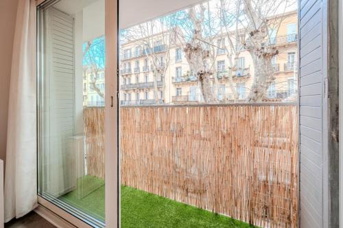 une porte en verre menant à un balcon avec de l'herbe verte. dans l'établissement Le Cocon du Mourillon, à Toulon