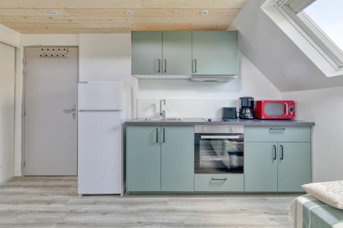 une cuisine avec des armoires vertes et un appareil rouge dans l'établissement La Dune de Sable Port Niché, à Pornichet