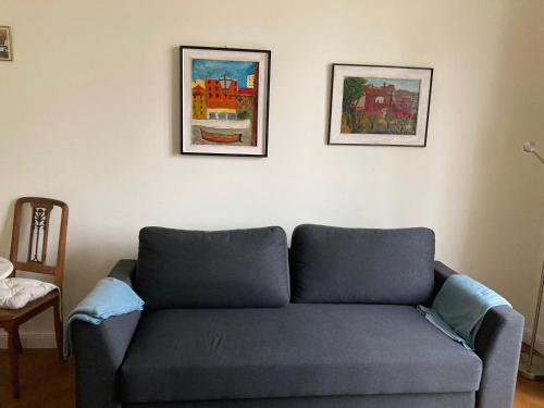a blue couch in a living room with two pictures on the wall at Wunderschöne Wohnung in Jugendstilvilla am Hafen in Nice