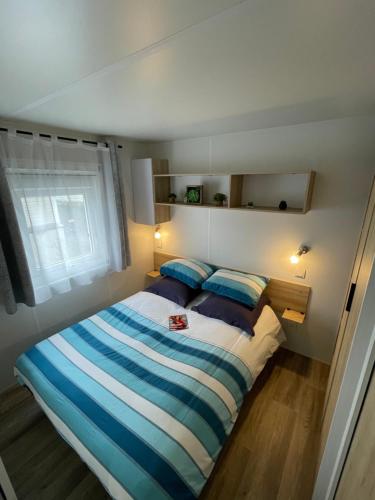une chambre avec un lit à rayures bleues et blanches dans l'établissement Océan Soleil Relax Mobil Home LaPignade 4 étoiles, à Ronce-les-Bains