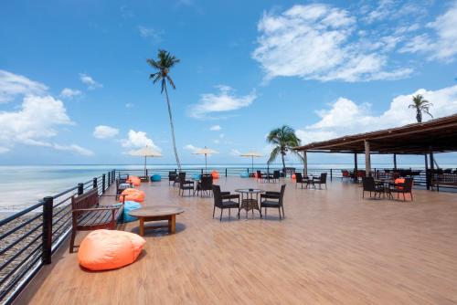 a restaurant on the beach with tables and chairs at Royal Mandarin Hotel & Resort in Pwani Mchangani