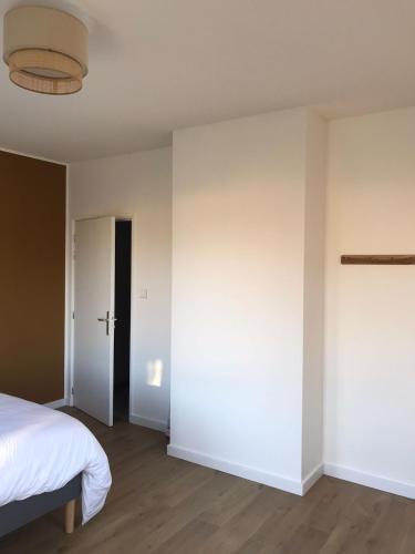 une chambre avec un lit et un mur blanc dans l'établissement Maison Origines pour 2 personnes, à Heudicourt