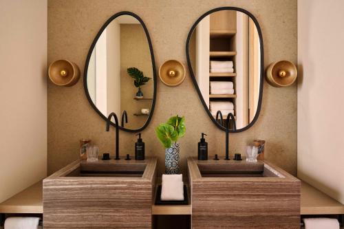 a bathroom with two sinks and two mirrors at Rosewood Miyakojima in Miyako Island