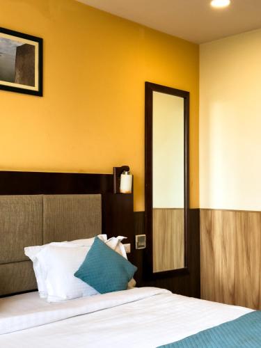 a bedroom with a bed with yellow walls and a mirror at Hotel Royal Palm - A Budget Hotel in Udaipur in Udaipur