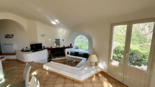 un salon avec un canapé blanc et une cheminée dans l'établissement Villa Porra 100m2, pleine nature, piscine, vue mer, à Porto-Vecchio