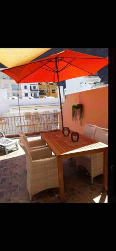 a wooden table with an umbrella on a patio at Große Dachwohnung mit Blick auf das Meer in Valle Gran Rey