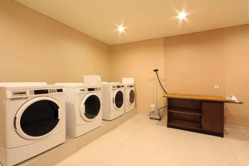 a laundry room with three washing machines and a table at Dwijaya House of Pakubuwono in Jakarta