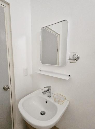 a white bathroom with a sink and a mirror at Lio Palm Villas in Langi-langiban