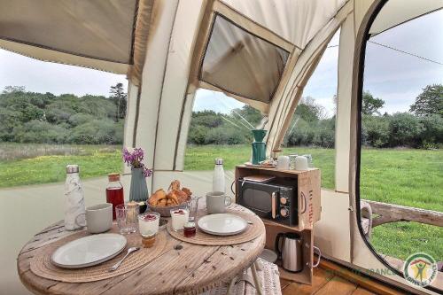 a table in a tent with a coffee maker and a microwave at La caleche de kergomar in Ploumilliau