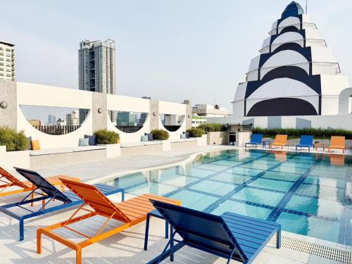 a pool on the rooftop of a building with chairs at The Quarter Saphankhwai by UHG in Bangkok