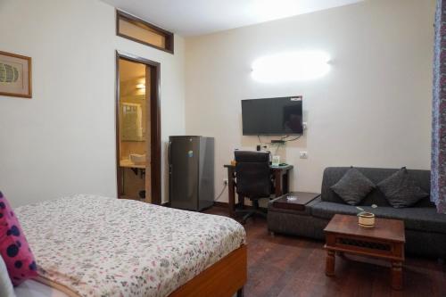 a bedroom with a bed and a couch and a tv at Perch Arbor Suites in Gurgaon