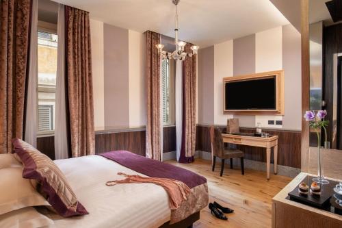 a hotel room with a bed and a desk and a television at The Inn at the Spanish Steps Luxury Collection - The Inn at the Spanish Steps in Rome