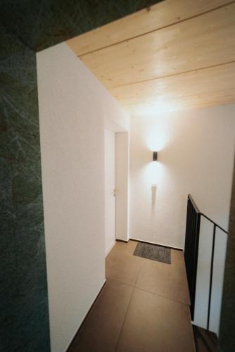 a hallway with a door and a light on the wall at Neue helle Wohnung mit Bergblick am Eingang der Jungfrau Region und Berner Oberland in Aeschi bei Spiez