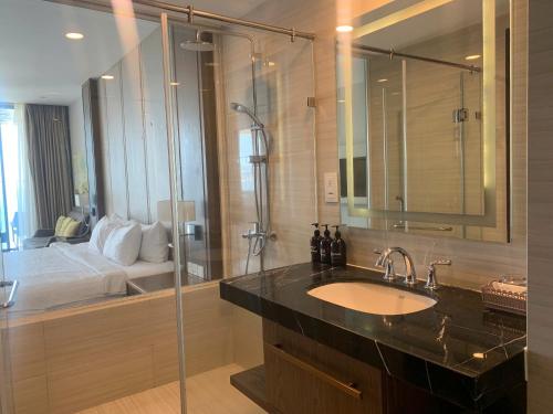 Un baño con lavabo y ducha y una cama. en Panorama Nha Trang Skydream, en Nha Trang