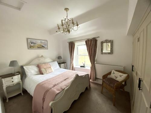 a bedroom with a bed and a chandelier and a window at Holme House Cottage in Oakworth