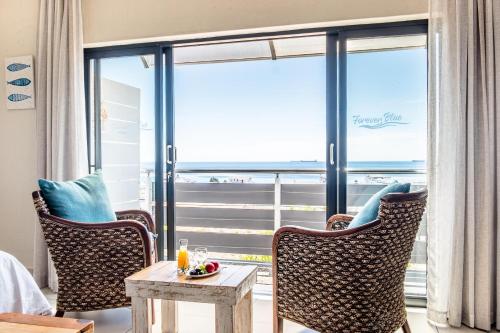 a room with two chairs and a table and a large window at Forever Blue in St Helena Bay